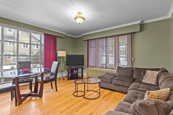 Spacious Living Area: Bright, open-concept living room featuring warm hardwood floors, a comfortable sectional sofa, and a dedicated dining nook—perfect for relaxing after a day of exploring.