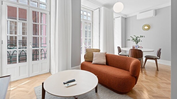 Ein modernes Wohnzimmer mit einer Couch, einem runden Couchtisch und einem Essbereich mit Tisch und Stühlen.