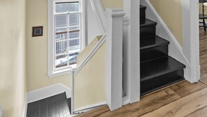 A staircase with white railings and black steps leading to a landing with a window.