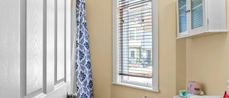 A small bathroom with a toilet, sink, and window with blinds.