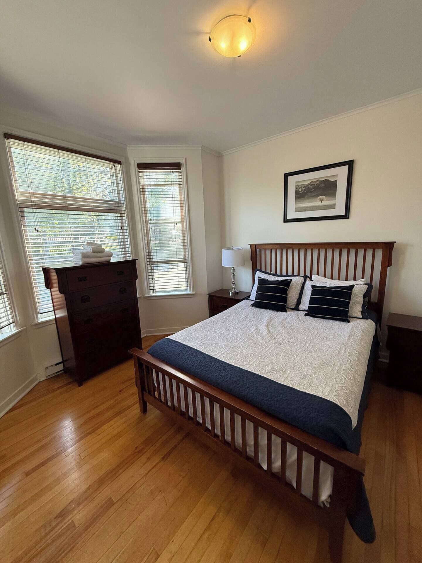 Un dormitorio con una cama de madera, un aparador y una mesita de noche.