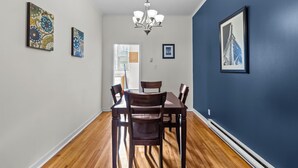A dining area with a wooden table and chairs, a chandelier, and artwork on the walls. - Charming 2BR Wi-Fi Off-Street Parking (St. John's)