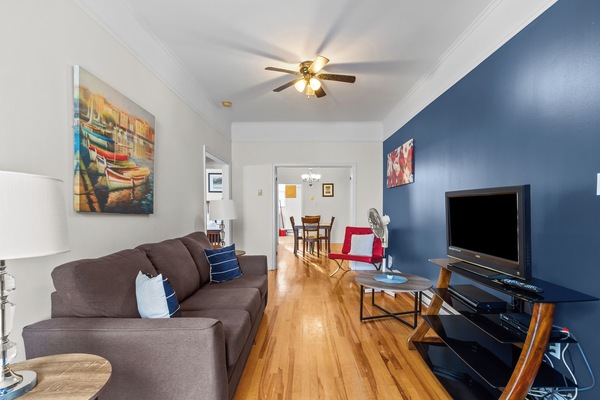 Relax in this bright living area featuring hardwood floors, a comfortable sofa, and a flat-screen TV. Perfect for unwinding after a day of exploring.