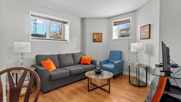 Un salon moderne avec un canapé gris, un fauteuil bleu et une table basse ronde.