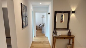 A hallway with wooden flooring, a wooden console table with a vase, and a mirror on the wall. - Modern vacation apartment in Marbach am Neckar in the immediate vicinity of the Schillerhöhe (Marbach am Neckar)