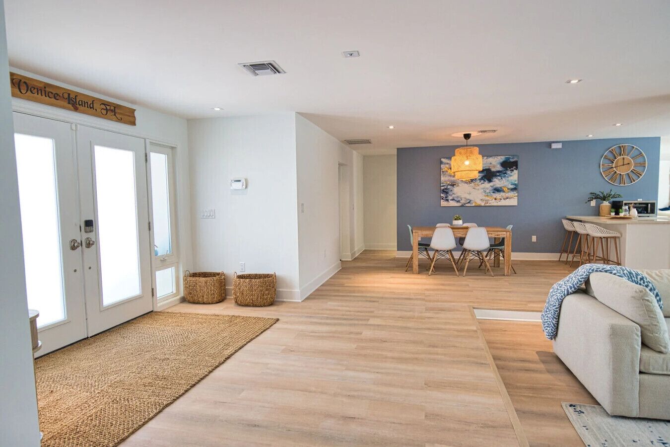 A spacious living area with a dining table and chairs, a sofa, and a kitchen area with a bar.