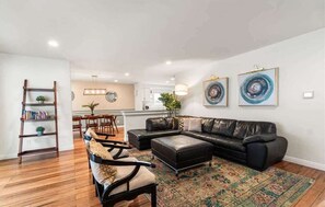 A living room with a black leather sofa, a patterned rug, and a wooden bookshelf.