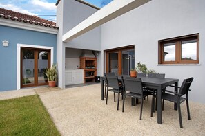 Une terrasse avec une table et des chaises, un four en briques et une plante en pot.