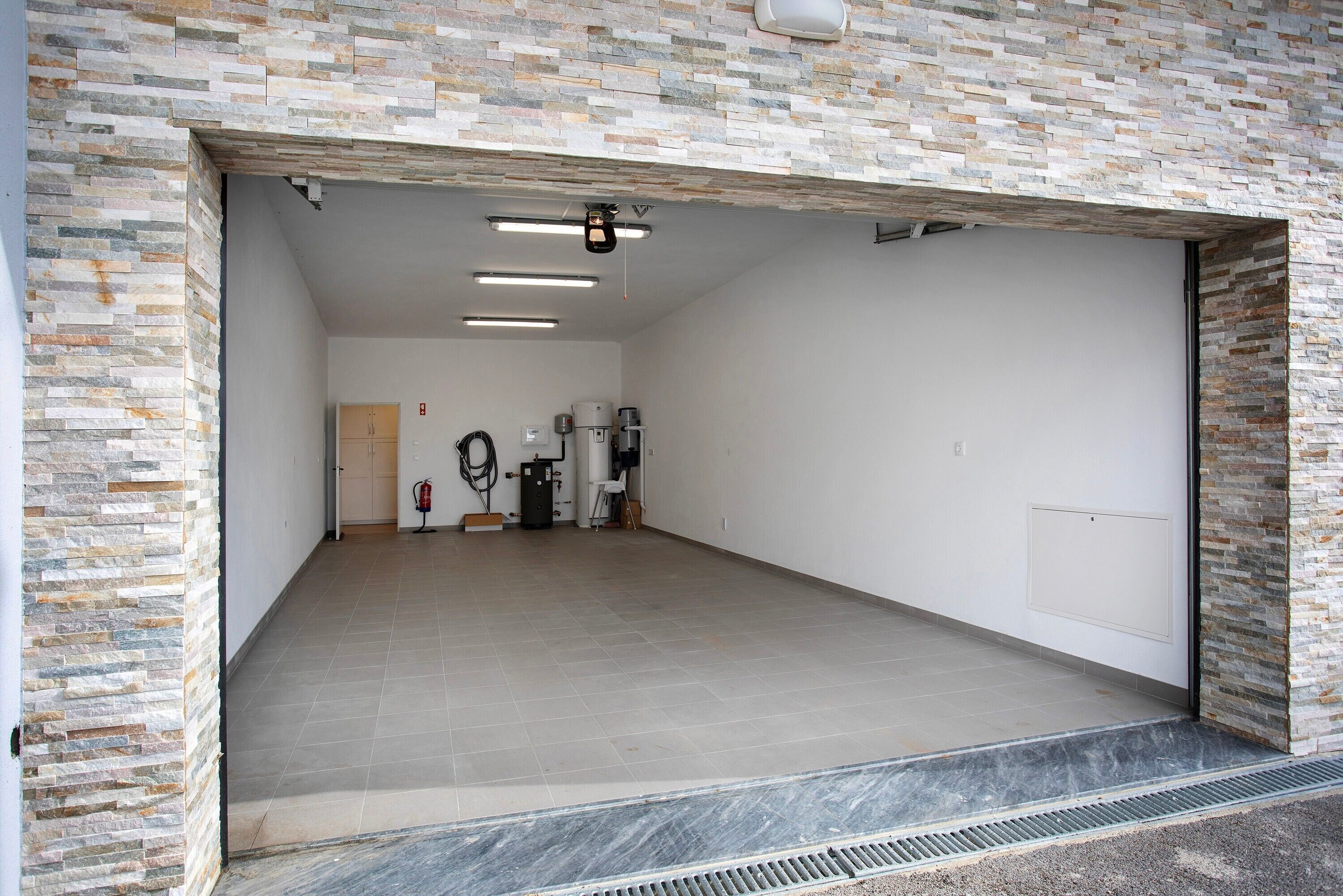 A spacious garage with a stone wall, a fire extinguisher, and a gas pump.