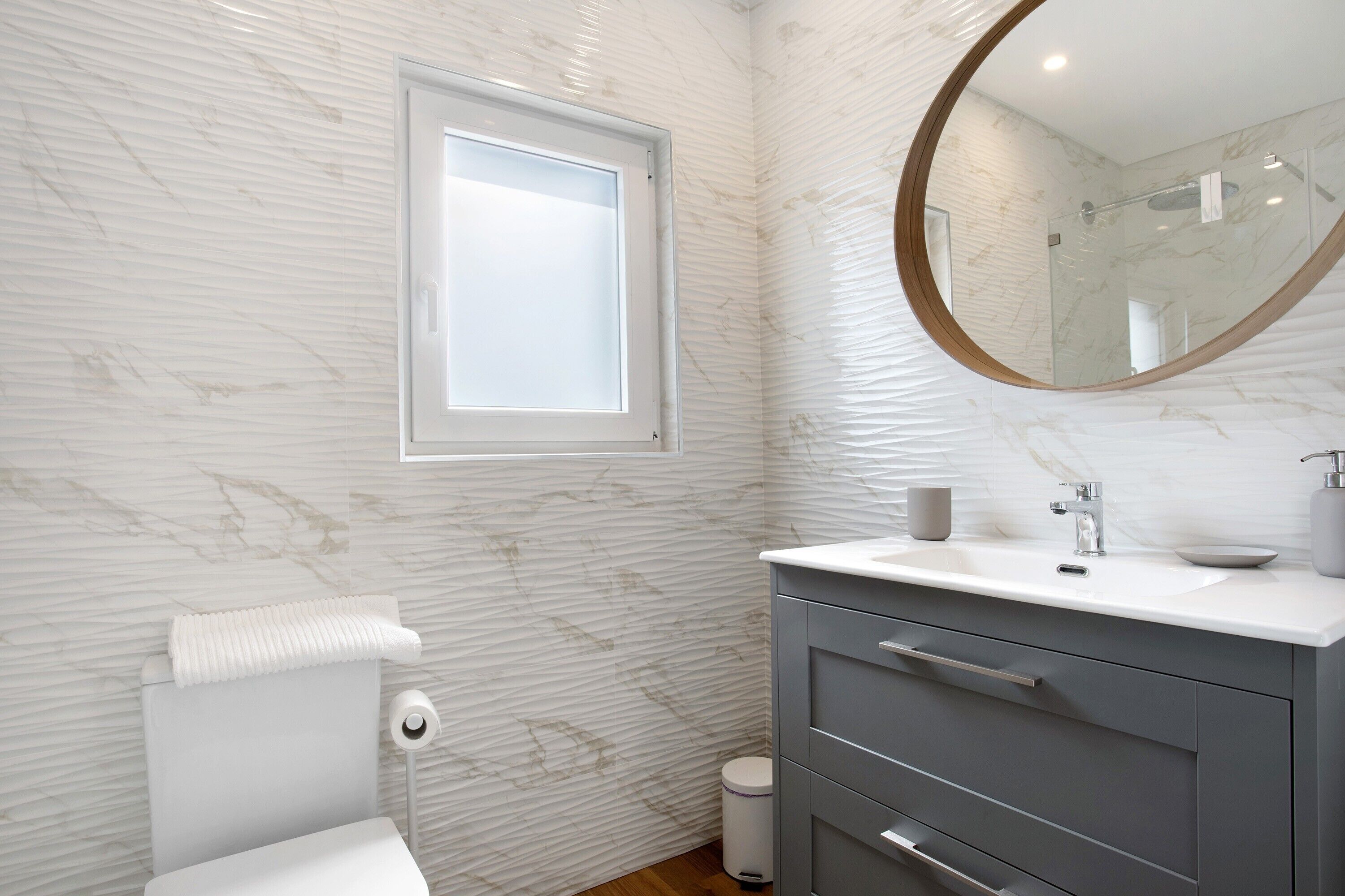 Un baño con inodoro, lavabo, espejo y ventana.