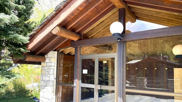 Un bâtiment en bois doté de grandes portes vitrées et d’un mur en pierre.