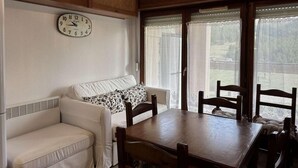 Ein gemütliches Zimmer mit einem weißen Sofa, einem Holztisch und einer Uhr an der Wand.