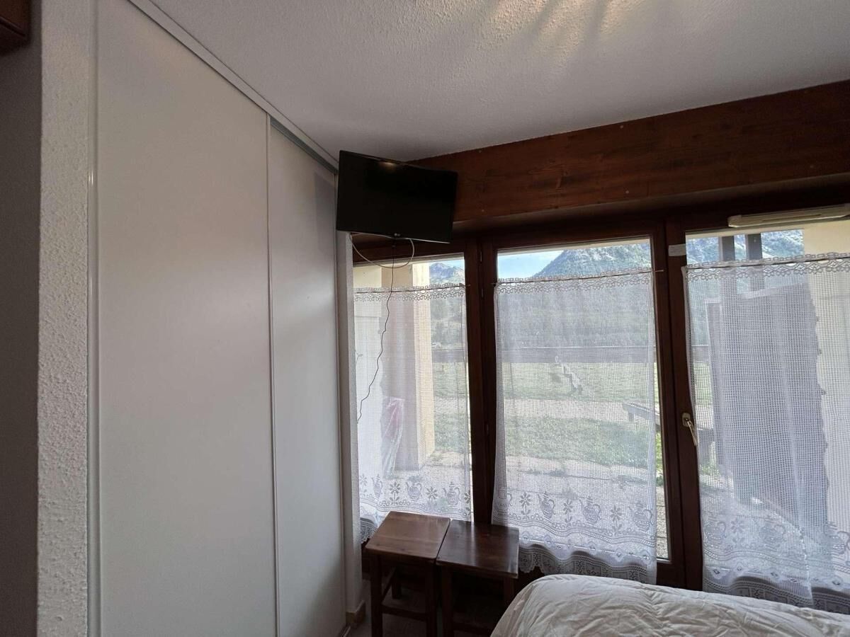 Une chambre à coucher avec un lit, une petite table et un téléviseur fixé au mur.
