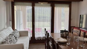 Ein gemütliches Wohnzimmer mit einer Couch, einem Esstisch und einem Fernseher.