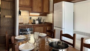 Eine Küche mit Holzausstattung, einem weißen Kühlschrank und einem Esstisch, gedeckt mit Tellern, Gläsern und einer Karaffe.