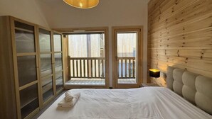 Una camera da letto con un letto grande, una testiera in legno, un balcone con ringhiera e un'ampia finestra.