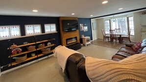 Una sala de estar con chimenea, televisor y comedor con mesa y sillas.