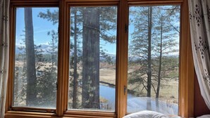 Un dormitorio con un amplio ventanal que ofrece vistas a un bosque y un lago.