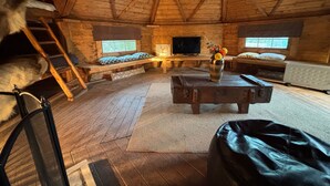 A cozy cabin with a loft bed, a television, a wooden coffee table, and a window with a view. - Hobbit Haven Hot Tub and Countryside Bliss (Gaerwen)