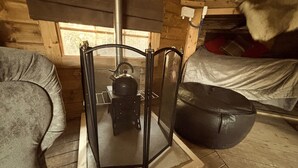 A cozy cabin room with a metal screen door, a wooden bench, and a window with a view of the outdoors. - Hobbit Haven Hot Tub and Countryside Bliss (Gaerwen)