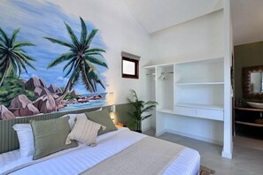 A bedroom with a bed, a mural of a beach scene, a wardrobe, and a bathroom with a sink and mirror. - Villa The Rock, Villa 12 - Adult Only (Koh Samui)