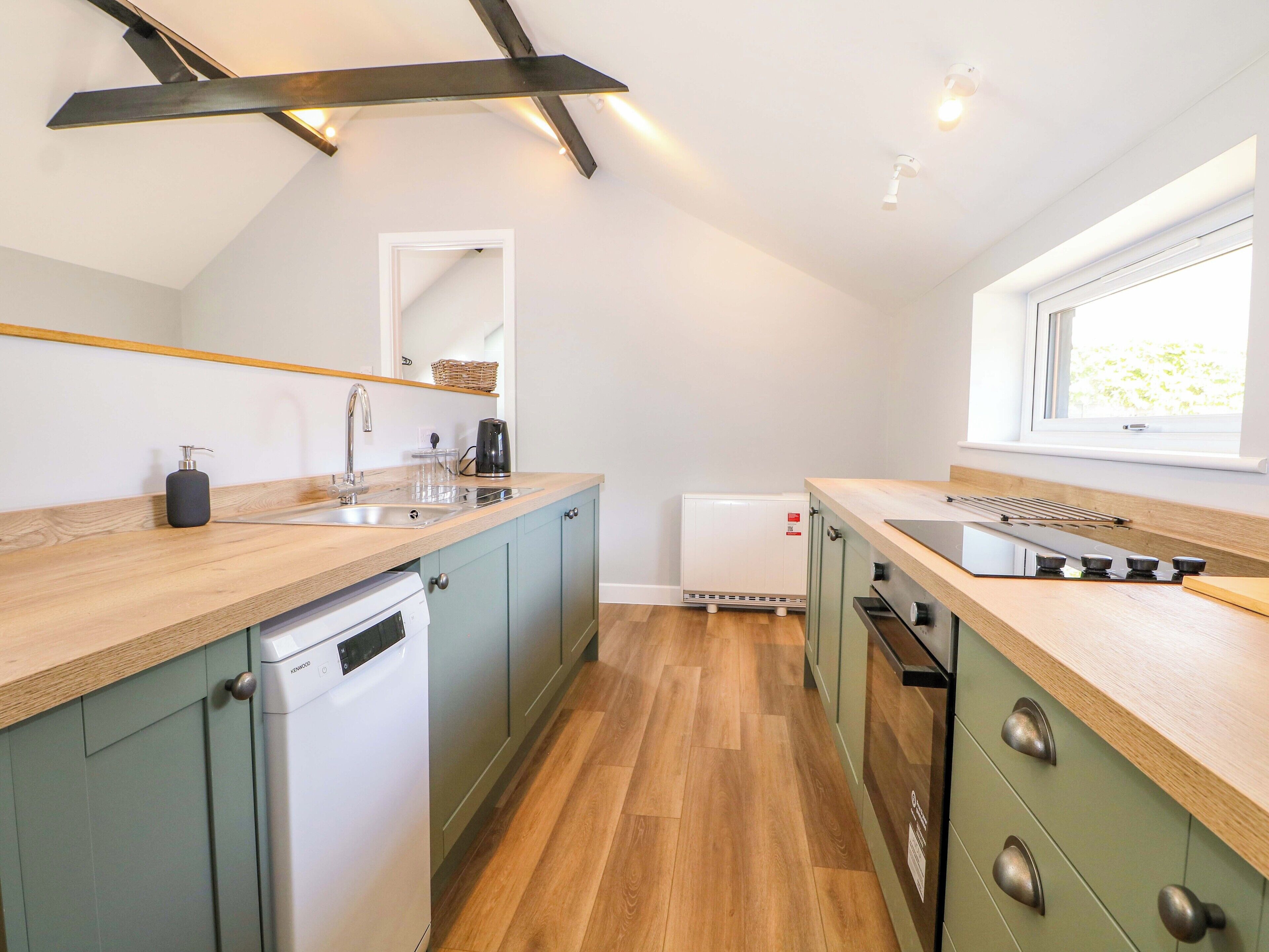 Una cucina moderna con un piano di lavoro in legno, lavastoviglie integrata e una finestra che permette l'ingresso di luce naturale.