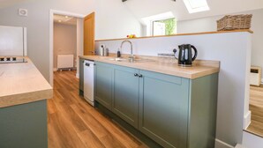 A modern kitchen with a central island, wooden flooring, and skylights. - The Old Parlour (Southampton)