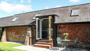 A brick house with a grey roof, a glass door, and a small patio with two chairs and a table. - The Old Parlour (Southampton)