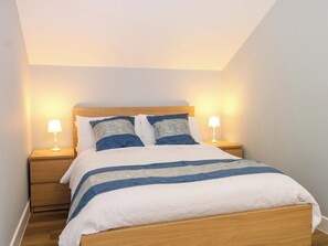 A neatly made bed with a striped bedspread, two bedside lamps, and a wooden headboard. - The Old Parlour (Southampton)