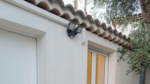 A white building with a tiled roof, a white door, and a window with a view. - Studio 4 persons (Le Cannet)