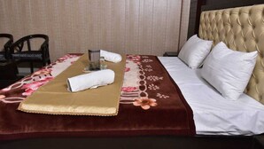 Un letto rifatto con cura, con copripiumino floreale, cuscini bianchi e una coperta in oro.
