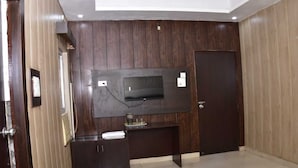 Una stanza con parete rivestita in legno scuro, una televisione a schermo piatto montata sopra un mobile in legno scuro e una porta sulla destra.