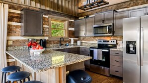 A modern kitchen with granite countertops, stainless steel appliances, and wooden accents. - Secluded Couples' Cabin - Fire pit, Hot Tub, Location, Views (Gatlinburg)