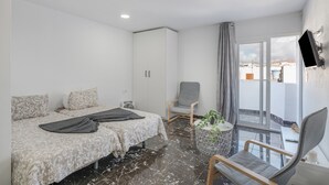 A bedroom with two beds, a chair, a TV, and a balcony with a view. - Casa Sofia - Apartment 1 with Mountain Views, Balcony and Wi-Fi (Arrecife)