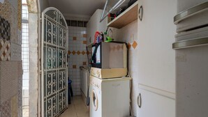 A compact kitchen with a washing machine, a refrigerator, and a microwave. - Apto Pet Friendly c Churrasqueira - Praia do Morro (Guarapari)