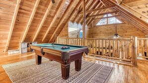 A wooden interior with a pool table, ceiling fan, and wooden railing. - Cozy Cabin with Amazing Views! Sleeps 8! Private Hot Tub! Resort Pools/Mini Golf (Sevierville)