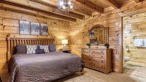 A wooden cabin bedroom with a bed, dresser, mirror, and wall-mounted toilet. - Cozy Cabin with Amazing Views! Sleeps 8! Private Hot Tub! Resort Pools/Mini Golf (Sevierville)