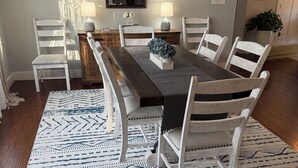 A dining room with a rectangular table, white chairs, a patterned rug, and a decorative ceiling light fixture. - Cozy Modern Farmhouse (Port Matilda)