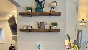 A kitchen with a central island, two barstools, and decorative items on shelves. - Cozy Modern Farmhouse (Port Matilda)