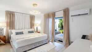 Un dormitorio moderno con una cama grande, lámparas de noche, un equipo de aire acondicionado y vistas al exterior.