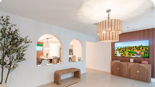 Una sala de estar moderna con un televisor grande, un banco tejido y una lámpara colgante.