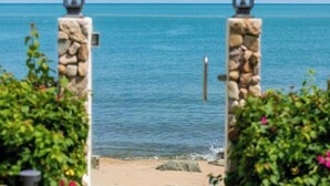 A view of a beach with a stone pillar and a lantern, surrounded by greenery. - Luxury Beachfront Pool Villa - Finu@Samui (Koh Samui)
