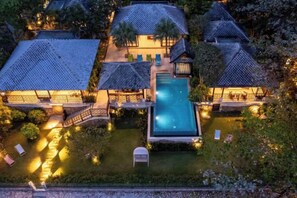 A resort with multiple buildings, a central swimming pool, and well-lit outdoor areas. - Luxury Beachfront Pool Villa - Finu@Samui (Koh Samui)