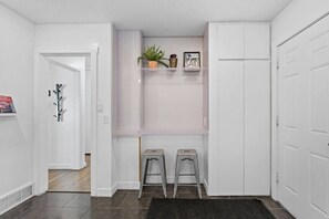 A hallway with a coat rack, two stools, a plant, and a sign on a shelf. - Airdream Cottage/Gated Garage-HotTub Laundry W&D (Salt Lake City)