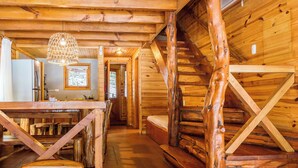 A rustic wooden cabin interior with a dining area, a staircase, and a hallway leading to a bedroom. - BOG Torres del Bayo (Villa La Angostura)