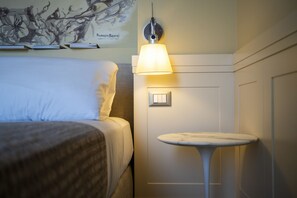 Et hotelværelse med en seng, et lille bord, en lampe på væggen og en dør med lyskontakt.