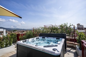 A hot tub on a rooftop terrace with a city view.