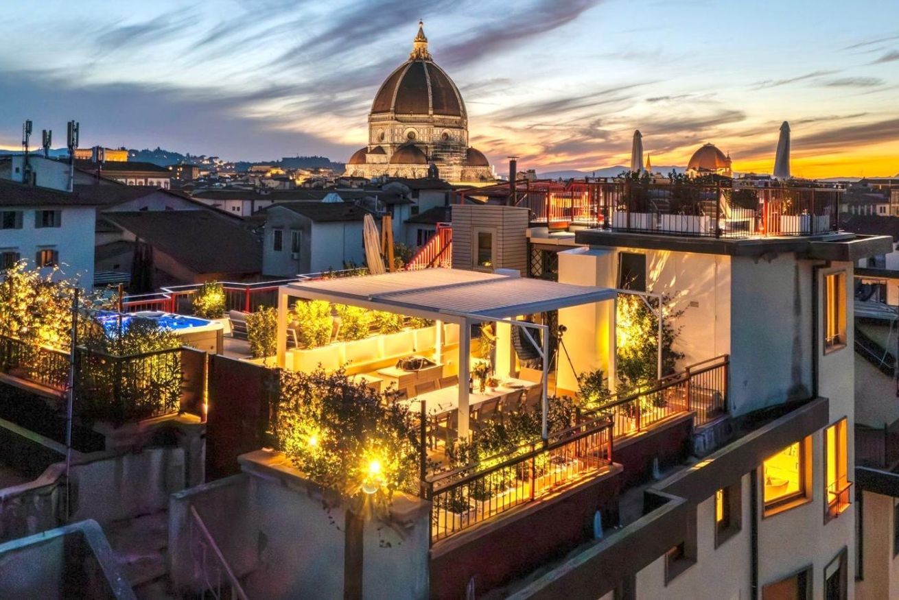 Une terrasse sur le toit avec des sièges en plein air, une vue sur un bâtiment en forme de dôme et sur les immeubles environnants.