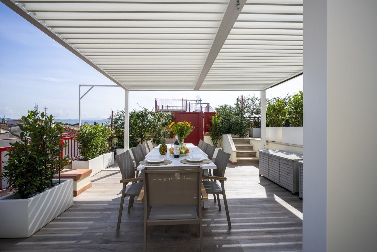 Eine Terrasse im Freien mit Esstisch und Stühlen, überdacht mit einem weißen Baldachin.