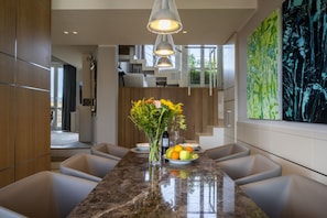 A modern dining area with a marble countertop, a vase with flowers, and a fruit bowl.